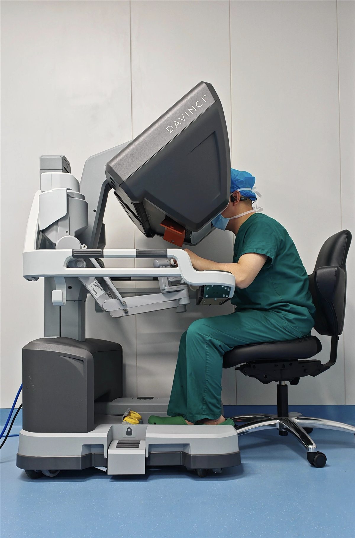 A surgeon operating a robotic-assisted surgical console in a clinical setting